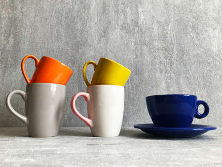 Colorful coffee cups on wooden table over grunge background.