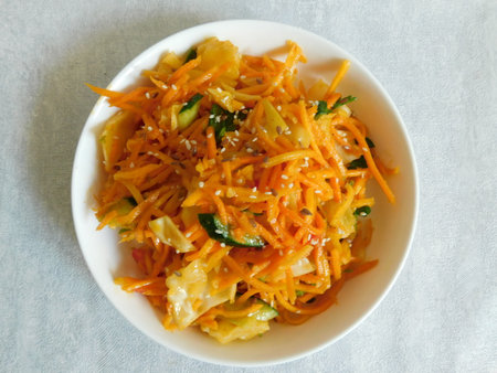 Korean cabbage and carrot salad with spices in a white plateの写真素材