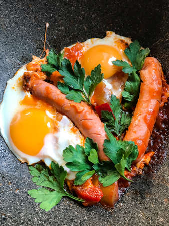 Frying pan with tasty cooked egg and sausages on table.の写真素材