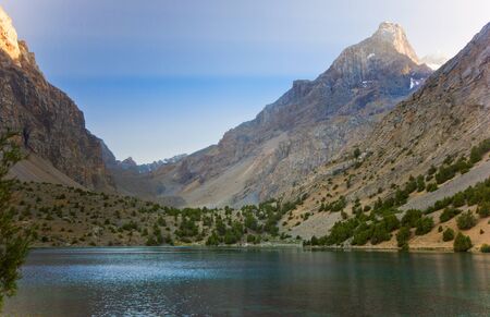 blue mountain lake at sunset surrounded by high peaksの写真素材
