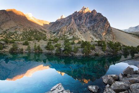 blue mountain lake at sunset surrounded by high peaksの写真素材