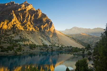 blue mountain lake at sunrise surrounded by high peaksの写真素材