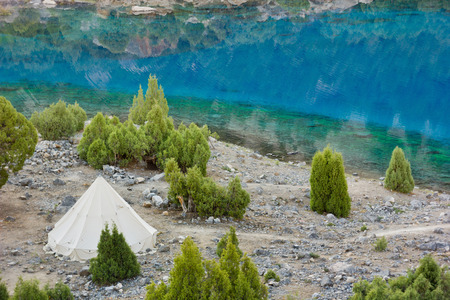 white pavilion on the bank of deep blue lake with green trees surroundedの写真素材