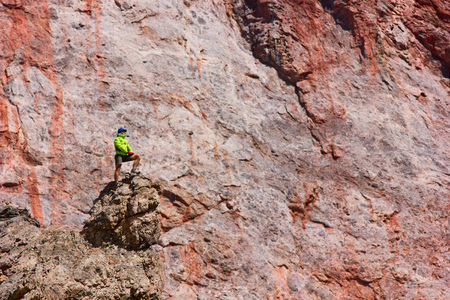 man standing on a cliff in mountains with red rock on backgroundの写真素材