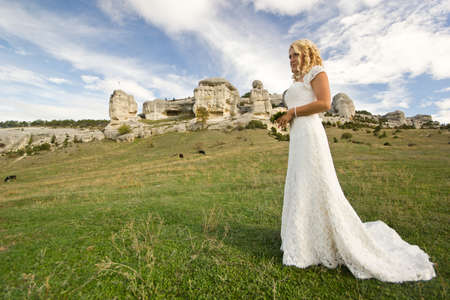 bride with bouquet in white wedding dress outdoor near rocksの写真素材