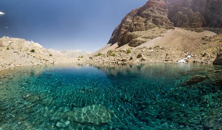 blue mountain lake at sunrise surrounded by high peaksの写真素材