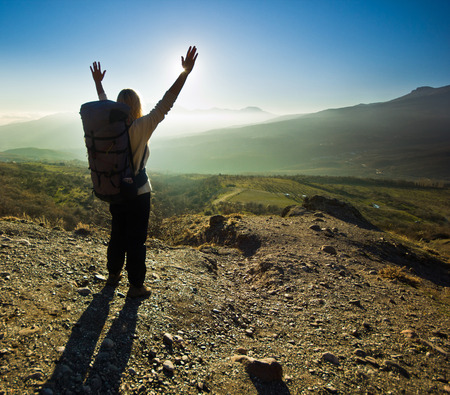 freedom girl with hands up in the mountains against sunの写真素材