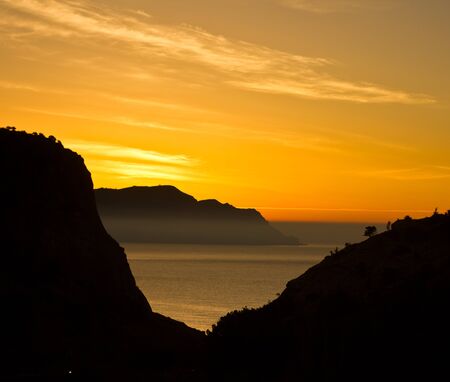 yellow sunrise above rocks on beach of Black Sea in Crimeaの写真素材