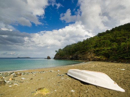 white boat on the beach with forest, sea and skyの写真素材