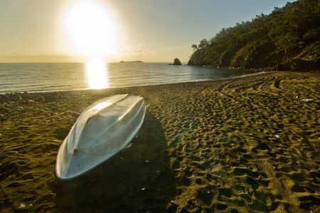 white boat on the beach with forest, sea and skyの写真素材