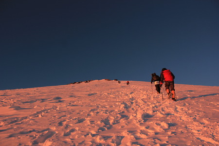 sunrise on elbrus mountain with climbers on snow slopesの写真素材