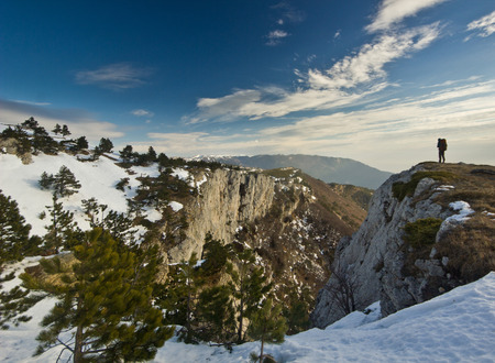 man  standing on a cliff in mountains at sunrise and looking on rocksの写真素材