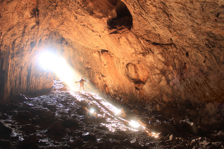 big shiny cave with small human standing near enterの写真素材