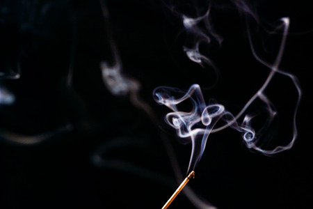 white smoke from aromatic indian sticks on a black backgroundの写真素材
