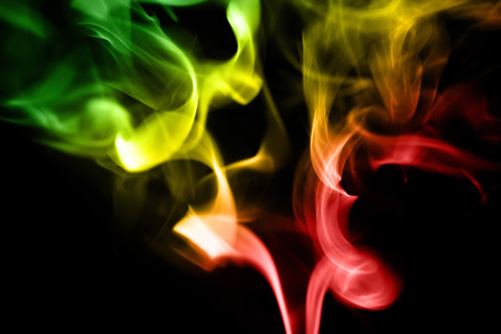 colored smoke from aromatic indian sticks on a black backgroundの写真素材