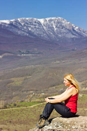 freedom girl sitting on a cliff and thinking in the mountainsの写真素材