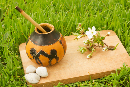 herbal tea mate with flowers and stones  on cutting wooden board with grass backgroundの写真素材