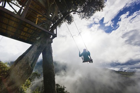 girl in swing in ecuador mountains near volcan with breakage with cloudy weatherの写真素材