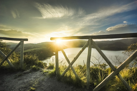fence and crater lake in sunset in ecuador against sunの写真素材