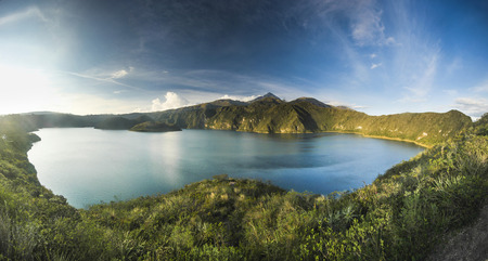 blue volcanic crater lake with two islands at sunset in ecuadorの写真素材
