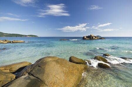 pure blue water of ocean beach with rocks on background and mountain shoreの写真素材