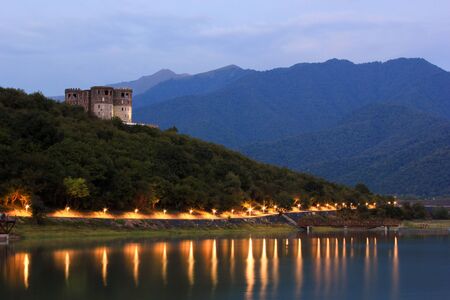 mountain lighted lake at sunset with castle on hillの写真素材