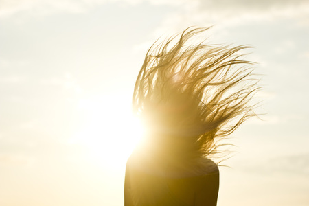 silhouette of girl's hair up against the yellow sun raysの写真素材