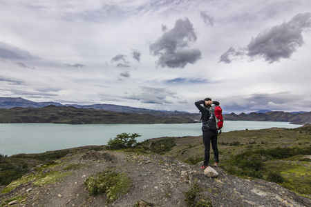 girl with backpack standing on the stone above lake in patagoniaの写真素材