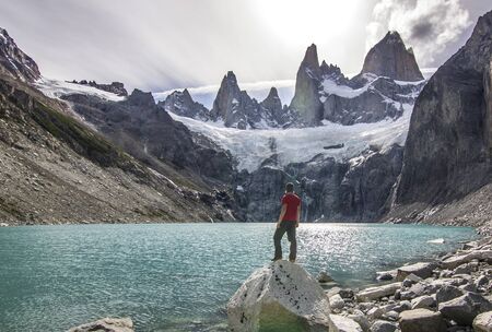 man standing on the stone above lake near fitz roy mountain, patagoniaの写真素材