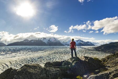 man standing on the stone above Grey glacier in patagonia at sunsetの写真素材