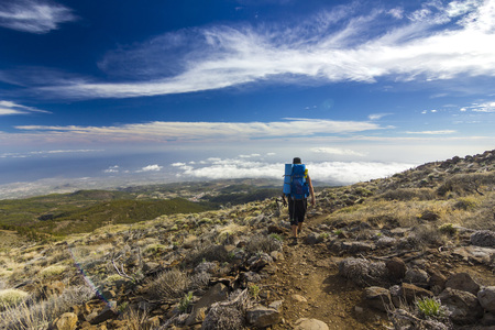man with backpack on path in semidesert with stones and blue skyの写真素材