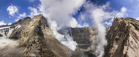 steaming crater of active volcano covered by snowの写真素材