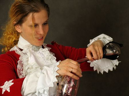 Woman in french clothes of 18 century with cup of red wineの写真素材