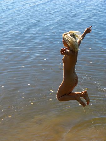 Blonde girl jumping into the waterの写真素材