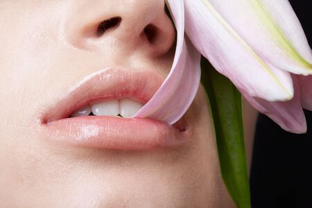 close-up portrait of half face of beautiful model nipping flower's petalの写真素材