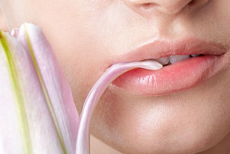 close-up portrait of half face of beautiful model nipping flower's petalの写真素材