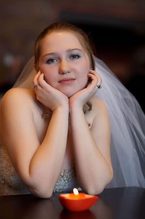 Young bride sitting before burning candleの写真素材