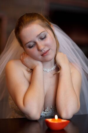Young bride sitting before burning candleの写真素材