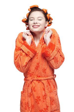portrait of beautiful girl in orange bathrobe with orange head rollers in hairの写真素材