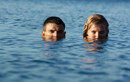 couple of swimmers coming up from the sea. lower parts of faces are in sea water