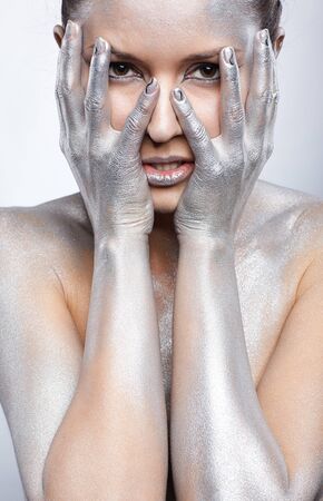 portrait of girl body painted with silver posing on grayの写真素材