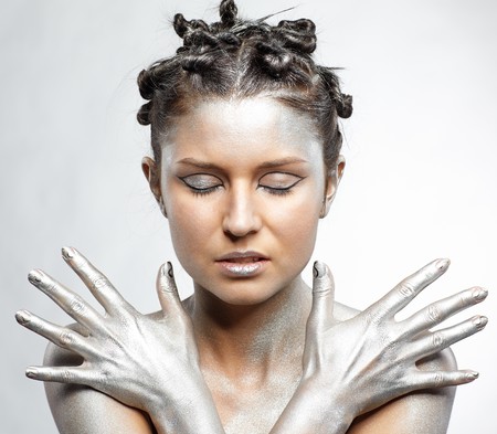 portrait of girl body painted with silver posing on grayの写真素材
