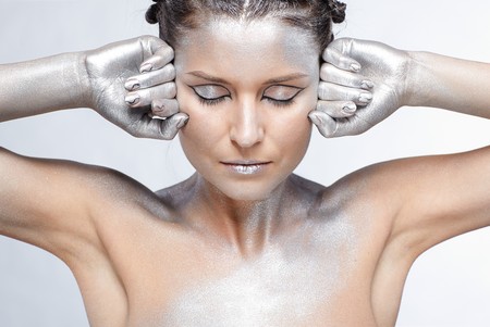 portrait of girl body painted with silver posing on grayの写真素材