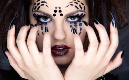 close up portrait of girl with spider bodyart of face zone and black finger-nailsの写真素材