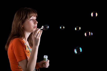 Young girl with bubbles isolated at the black background
