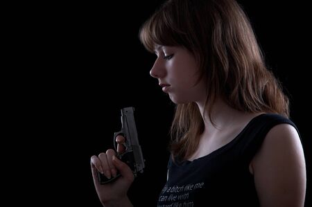 Girl with gun isolated at the black backgroundの写真素材
