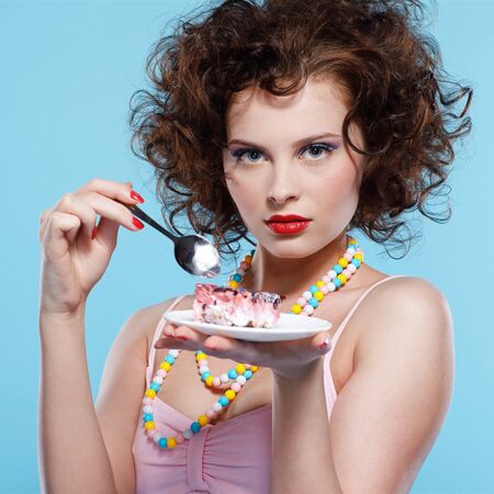 portrait of beautiful curly brunette girl with cakeの写真素材