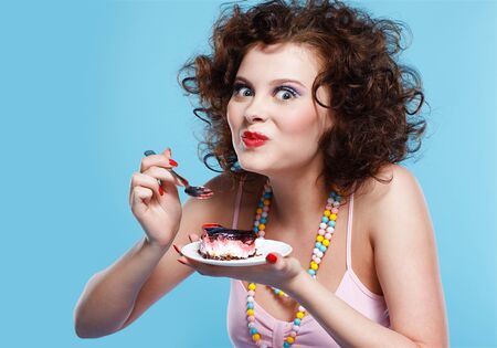 portrait of beautiful curly brunette girl eating cakeの写真素材