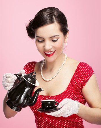 pin-up style portrait of beautiful brunette girl with teapot and cupの写真素材