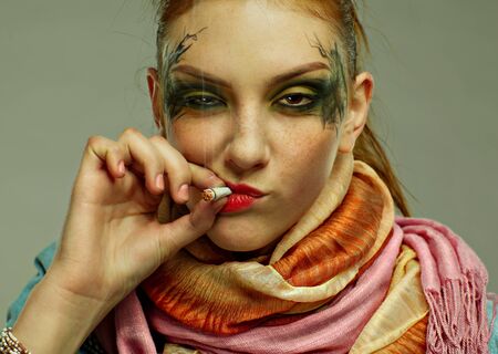 portrait of glam punk redhead girl smoking cigaretteの写真素材